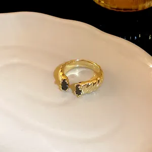Macro view of gold-plated dragon-shaped open ring with black zircons on white tray