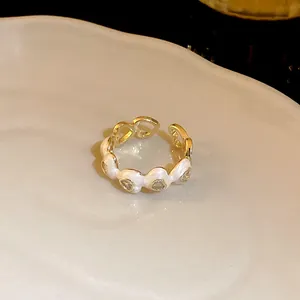 Detailed macro view of gold plated open ring featuring white enamel and zircon inlay