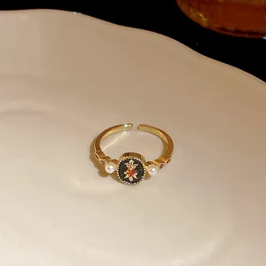 Close-up detail of vintage gold-plated open ring with star pattern, orange zircon, and white pearls