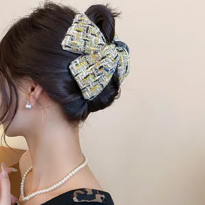 Detailed view of a chic yellow and black tweed bow hair claw clip styled on elegant hair