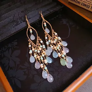 Bohemian beaded tassel earrings with colorful teardrop pendants on black velvet background