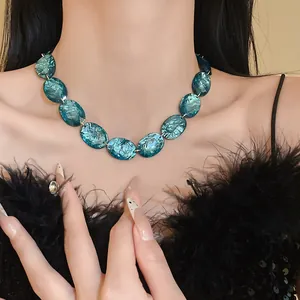 Close-up of turquoise oval resin necklace on model with black feather outfit.