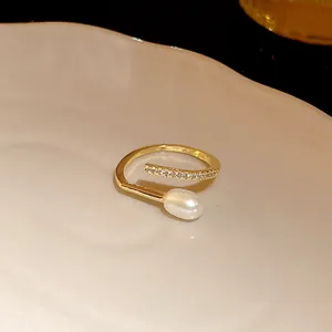 Close-up detail of an elegant gold plated open ring with a white pearl and pavé zircon.