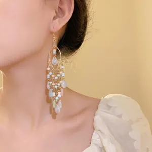 Elegant Bohemian tassel earrings featuring pastel seed beads and teardrop pendants on a model