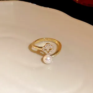 Detail view of a gold-plated open ring featuring a zircon four-leaf clover and pearl.