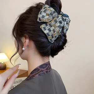 Elegant black and gold tweed bow hair claw clip for sophisticated bun hairstyles