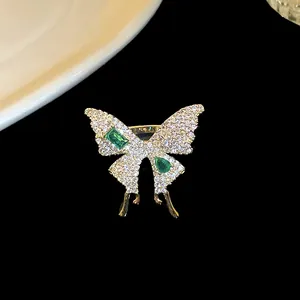 Detailed macro shot of a gold-plated butterfly ring with sparkling white and emerald green zircons.