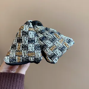 Macro view of elegant black and gold checkered tweed fabric on a triangle hair clip