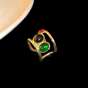Detailed view of a gold-plated ring featuring red, black, and green oval zircons