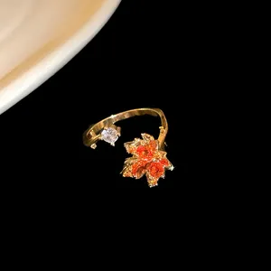 Close-up of gold-plated open ring with orange maple leaf and sparkling zircon