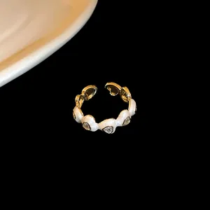 Close-up view of a gold-plated dragon-shaped open ring featuring white enamel and heart zircons.