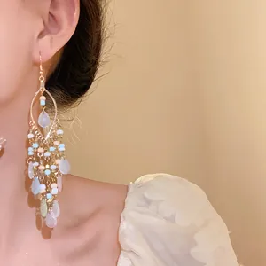 Detail of Bohemian style beaded earrings featuring water drop tassels on a model's ear.