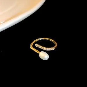Close-up detail view of gold-plated zircon open ring with an elegant white pearl accent
