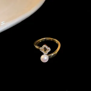 Detailed macro view of a gold plated open ring featuring a zircon clover and pearl.