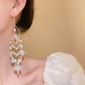 Detail shot of Bohemian teardrop tassel earrings with colorful rice beads on model.