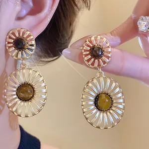 Close-up detail of vintage hollow oval gold earrings with tiger's eye stone