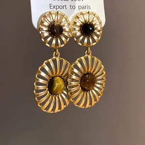 Detailed view of vintage style gold hollow oval drop earrings with polished tiger's eye stones