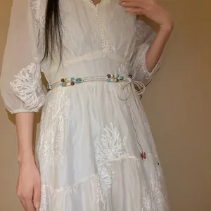 Detail of a handmade Bohemian woven waist chain featuring colorful acrylic beads on a white dress.