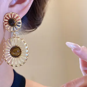 Detail view of vintage gold openwork drop earrings featuring natural tiger's eye stones