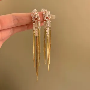 Dettaglio di eleganti orecchini lunghi a nappa in oro con pietre di zircone brillanti