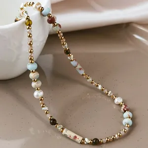 Detailed view of Baroque pearls and patterned cylindrical stone beads on a gold necklace