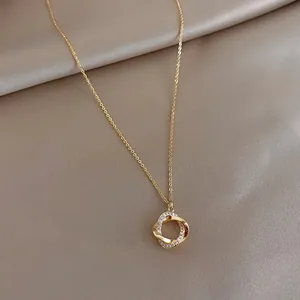 Nahaufnahme eines goldenen Anhängers mit zwei ineinandergreifenden Ringen und Kristallen