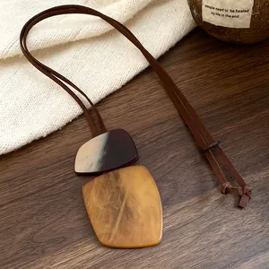 Detailed macro view of an ethnic style irregular horn plate necklace on a wooden background