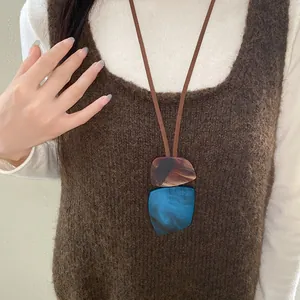 Detailed macro view of a retro irregular horn plate necklace on a brown knit vest