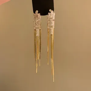 Vista dettagliata di eleganti orecchini a nappa lunga dorati con zirconi scintillanti.
