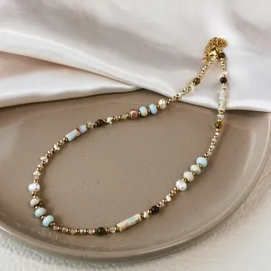Detail view of a Baroque pearl and stone cylinder beaded necklace on a beige tray