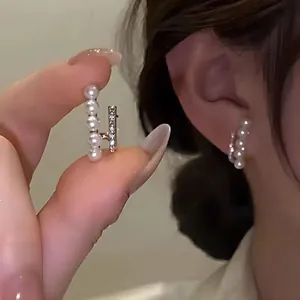 Detaillierte Nahaufnahme von eleganten Perlen- und Pavé-Ohrringen am Ohrläppchen