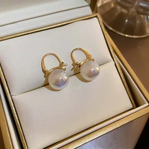 Nahaufnahme eleganter goldfarbener Creolen mit runden Perlen in einer Schmuckschatulle