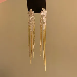 Dettaglio ravvicinato di eleganti orecchini a nappa d'oro con zirconi chiari