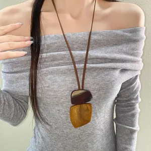 Detail of a vintage irregular horn plate pendant necklace styled with a grey ribbed top.