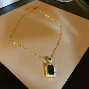 Detailed macro view of a vintage gold necklace featuring a square emerald green pendant