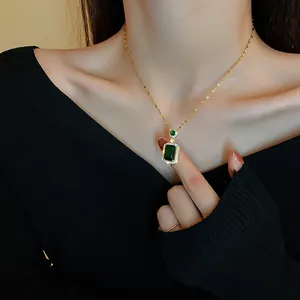 Detailed close-up of a vintage gold necklace with a square green emerald pendant and crystals