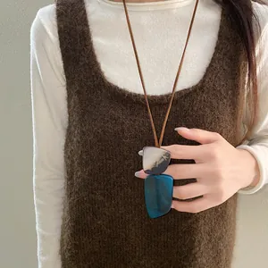Detailed view of an ethnic retro horn plate necklace worn on a fuzzy brown sweater.