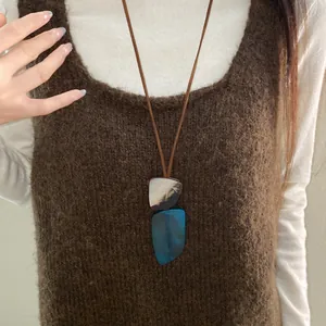 Close-up view of a folk vintage irregular horn plate necklace on a brown sweater