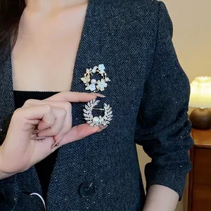 Broche élégante plaquée or avec zircons et perles, motifs floraux et papillons.