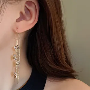 Close-up of elegant gold-plated flower tassel earrings featuring cubic zirconia