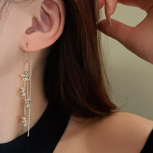 Close-up of gold-plated flower tassel earrings with sparkling cubic zirconia on model