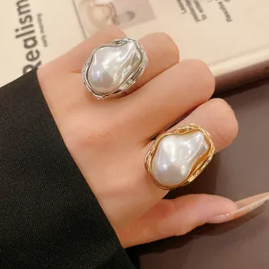 Close-up of elegant gold and silver rings featuring irregular baroque faux pearls.