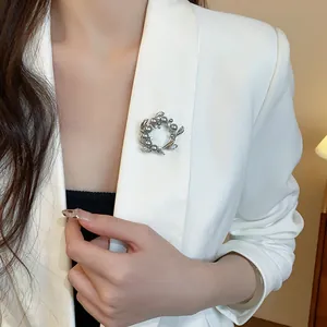Vue détaillée d'une élégante broche couronne en perles et zircons sur un blazer blanc