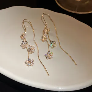 Detailed macro view of gold-plated long tassel earrings with sparkling zircon flowers