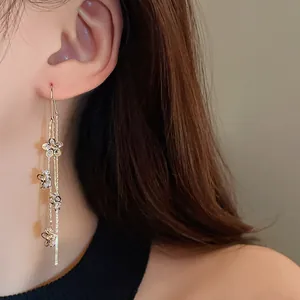 Close-up detail of elegant gold-plated tassel earrings with sparkling zircon flowers