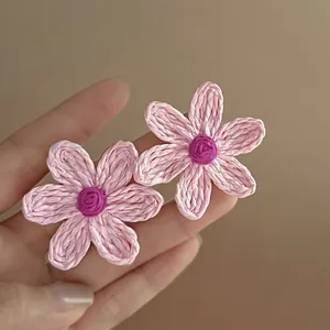 Detailed macro view of pink woven flower stud earrings with vibrant purple center