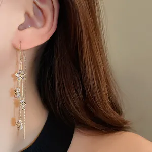 Detailed view of elegant gold-plated flower tassel earrings with sparkling zircons on model
