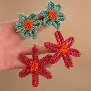Close-up of handmade colorful crochet flower drop earrings with vibrant orange beads detailing
