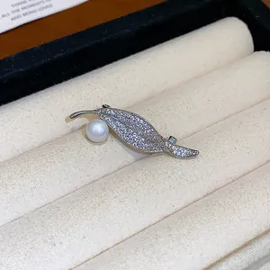 Broche feuille élégante avec pierres pavées étincelantes et une perle blanche lustrée.