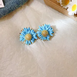 Close-up detail of vacation style sky blue daisy flower stud earrings with golden center